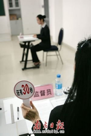 考場監(jiān)督員舉起限時牌提醒考生答題剩余時間。南方日報記者魯力 攝